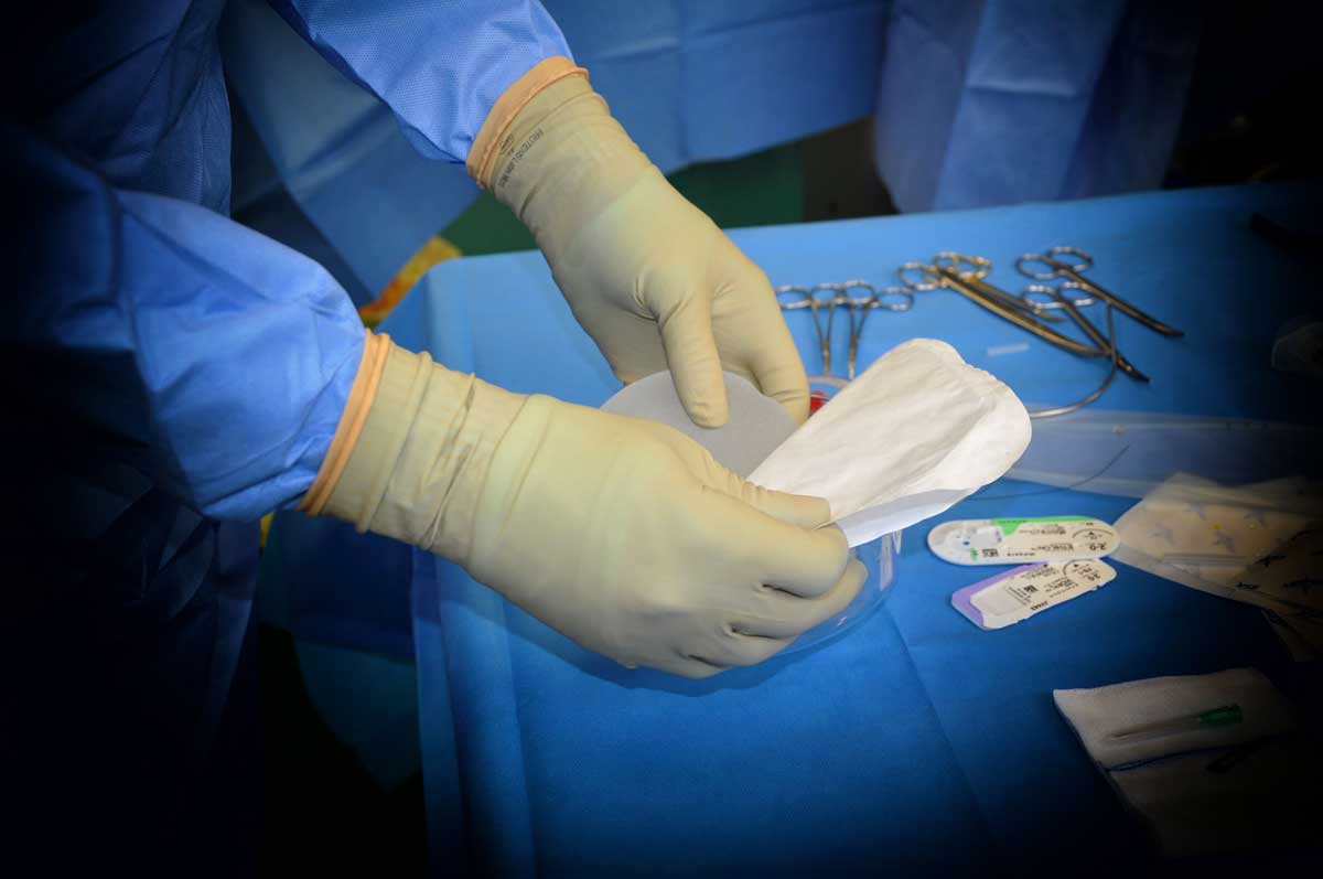 The Gloved Hands Of A Doctor Preparing A Breast Implant